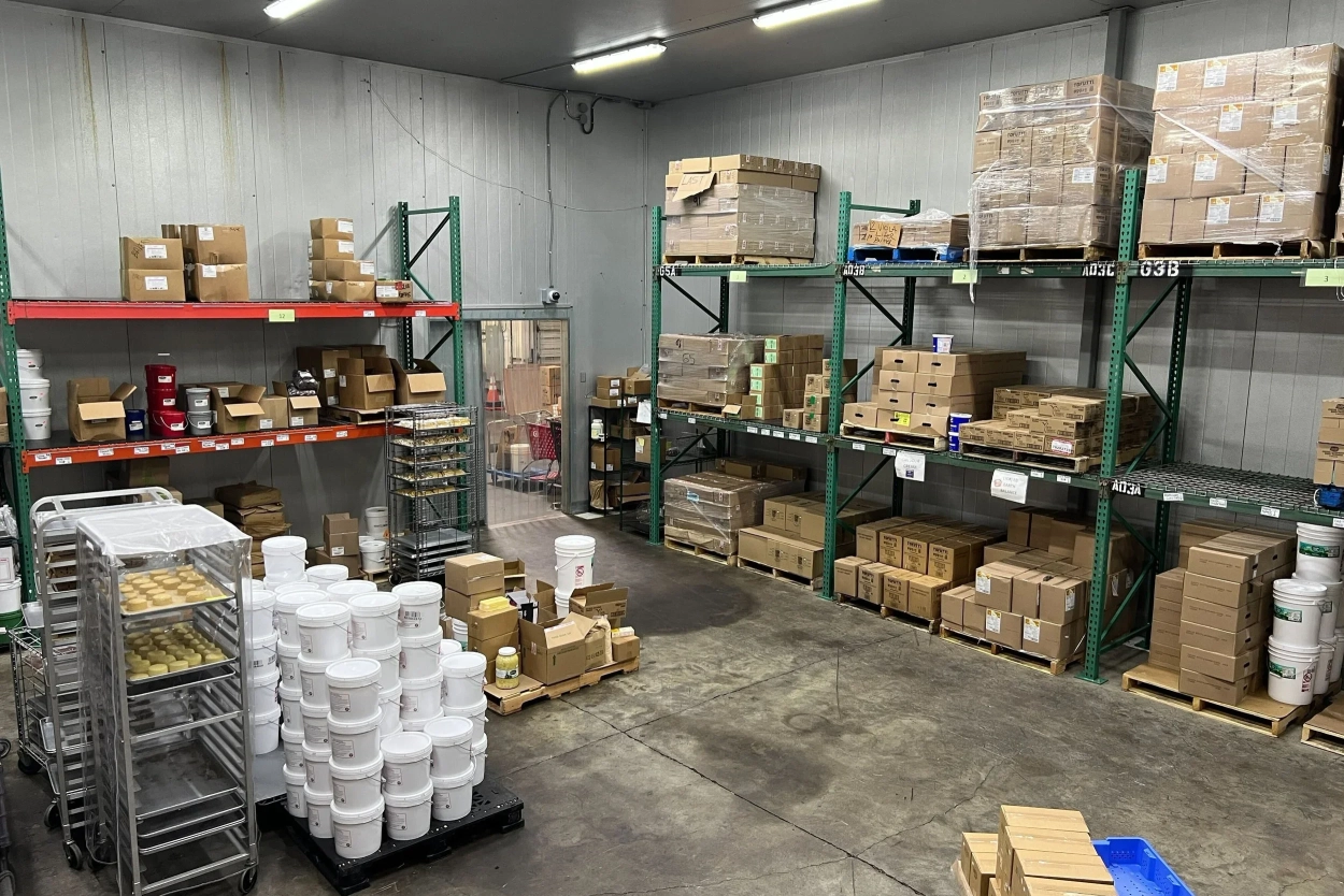 A hand holds a full pint glass of beer that has the wordmark Setouchi printed on it. In the background is a wall menu composed of black numbered signs with different beers listed on them.